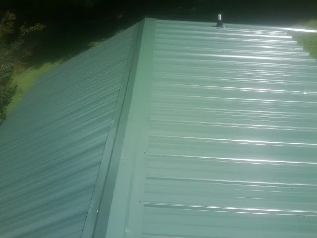New green metal panels meeting at the ridge of a roof — Flat Roof Repair work by our crew in The Colony