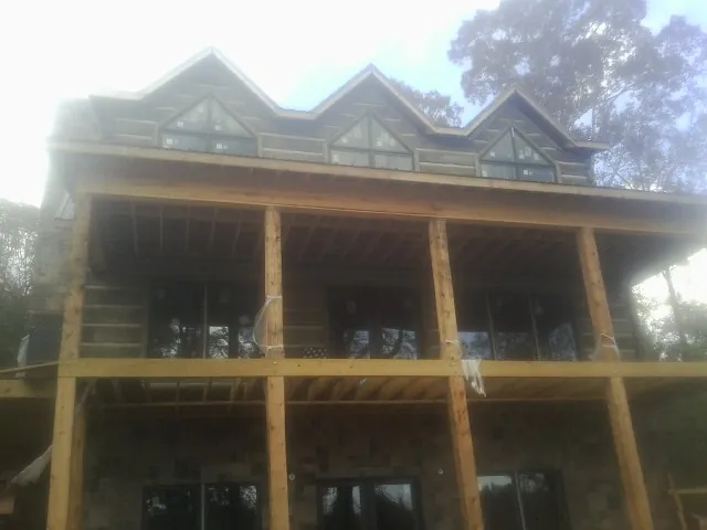 Dormers and porch framing on a large log home under construction — Roof Coating work by our crew in The Colony