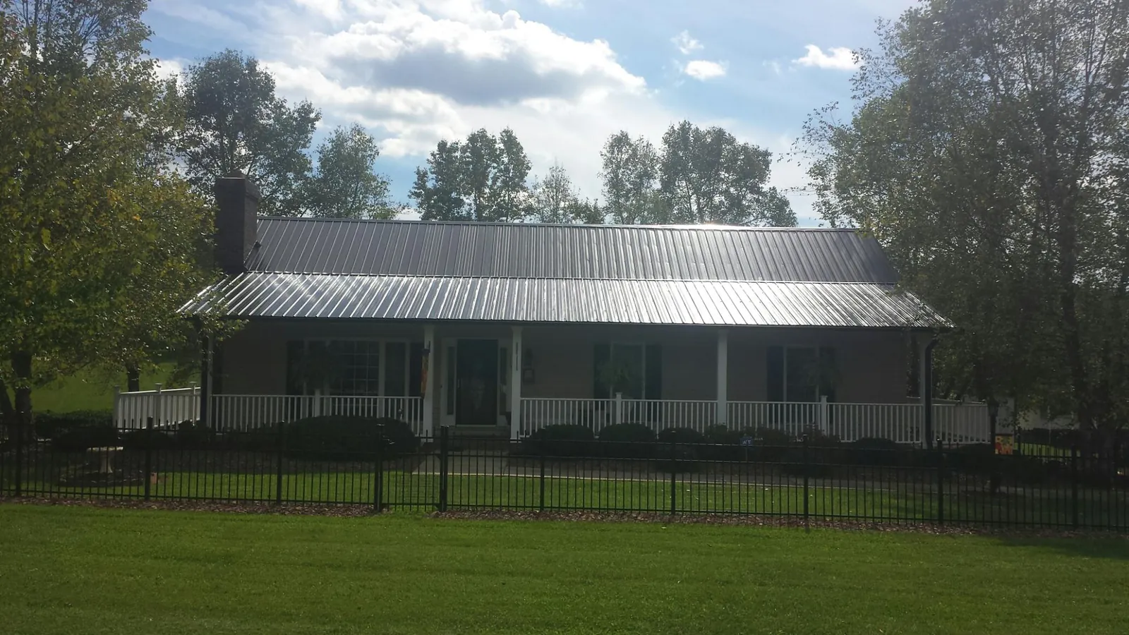 Gray metal roof on a brick ranch with a full width front porch — Gutter Guard Installation work by our crew in The Colony