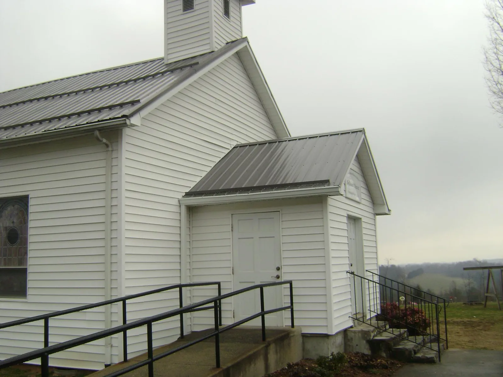Gray metal roof on a white clapboard church with a steeple in The Colony