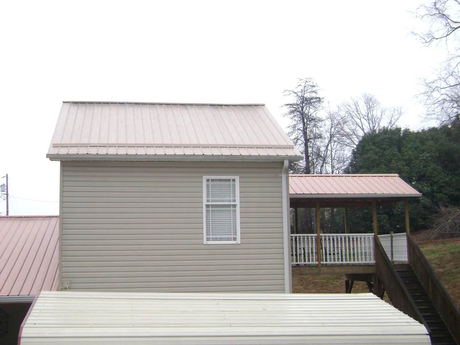Tan metal roofs on a two story addition and attached porch, from a Roof Replacement job in The Colony