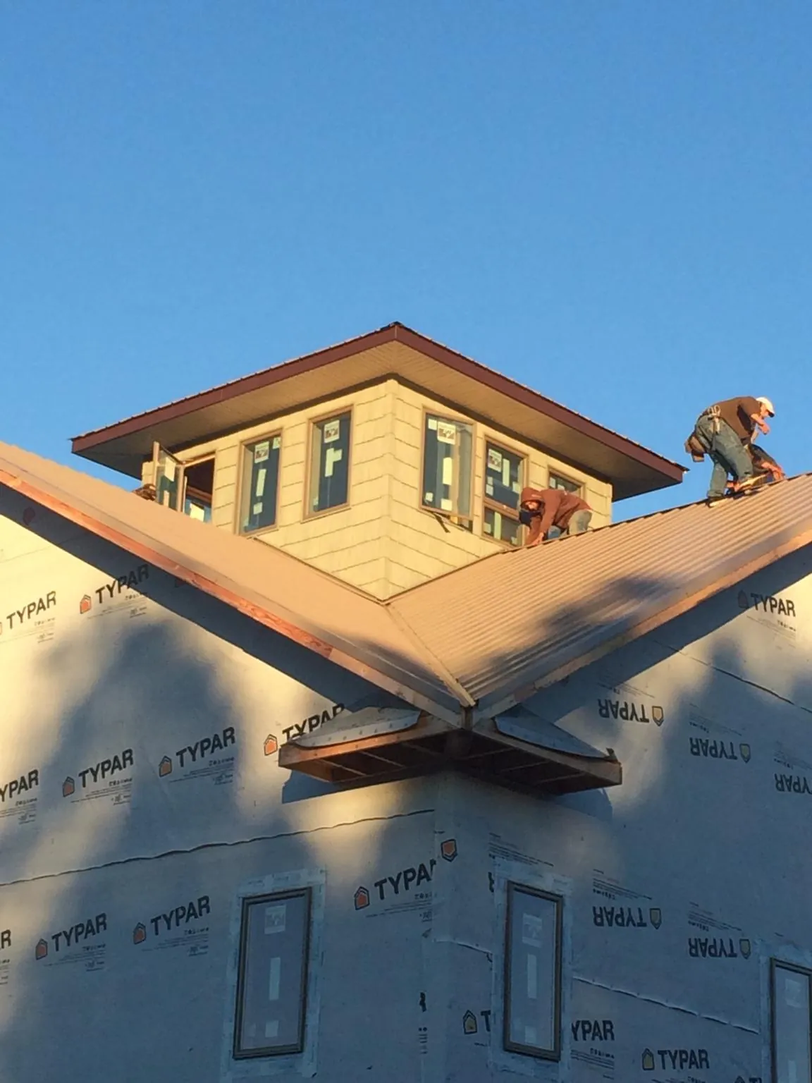 Roofers working around a rooftop cupola on a new metal roof at sunset — Roof Waterproofing in The Colony by Roofing Brothers